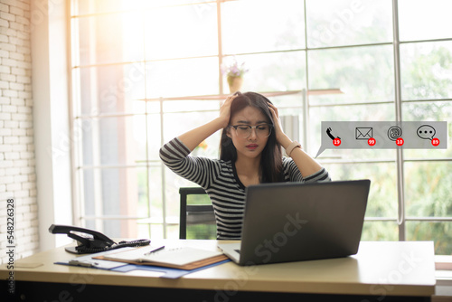 Asian businesswoman feeling stressed and tired from work with social media notification alert. Tired overworked business woman sleeps in office.