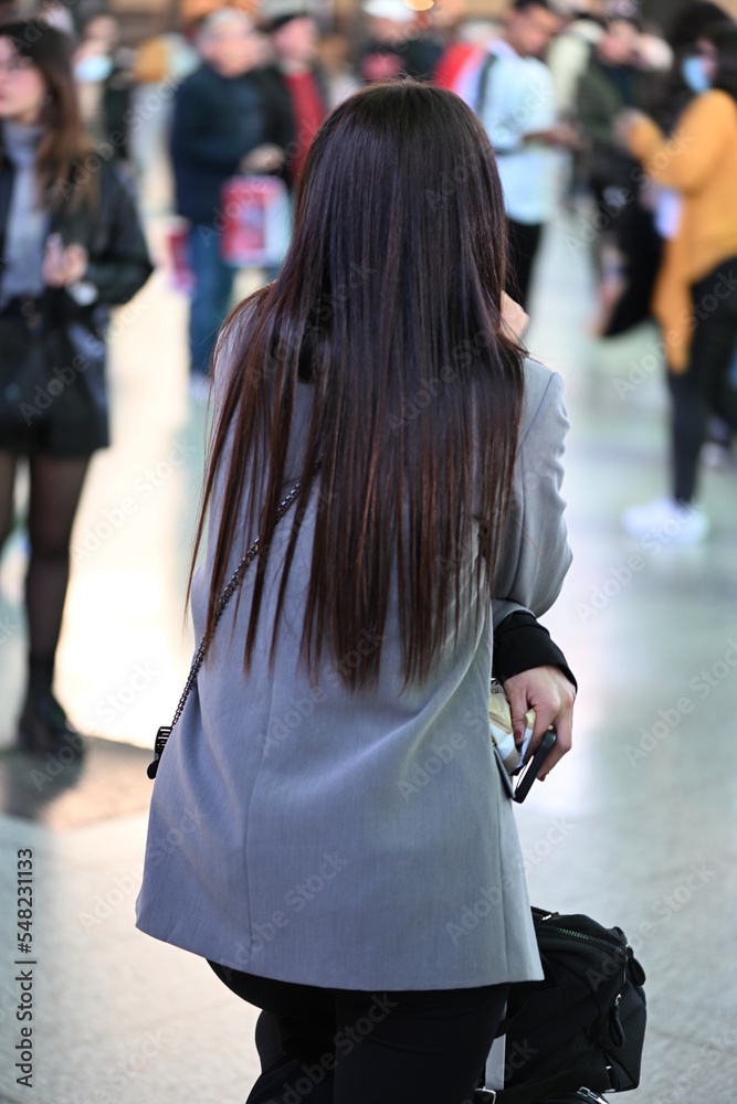 Fototapeta premium A young woman with long brown hair is waiting for her train in Valencia-Spain.