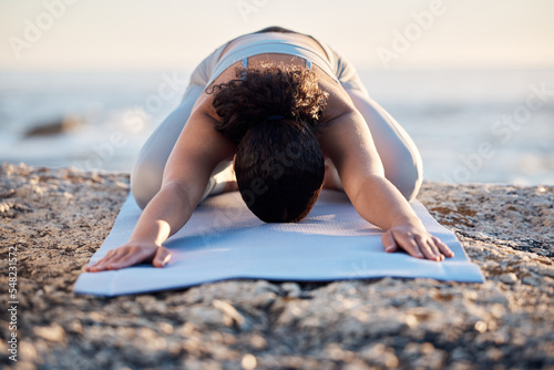 Yoga, meditate and fitness with a woman on a rock at the beach for mental health, wellness or exercise. Training, workout and meditation with a female athlete stretching outdoor in nature for health