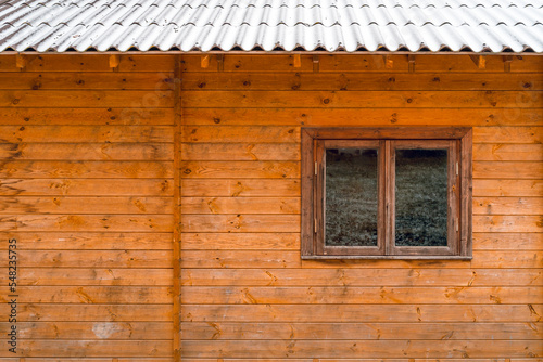 Window of an ecological wooden house with a snowy roof