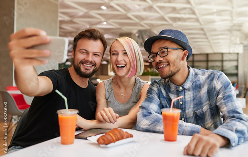 Happy diverse friends taking selfie in restaurant