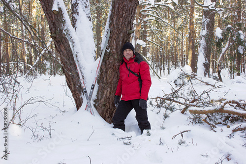 Man walked through a snowy  forest,  tired and leaning against a tree photo