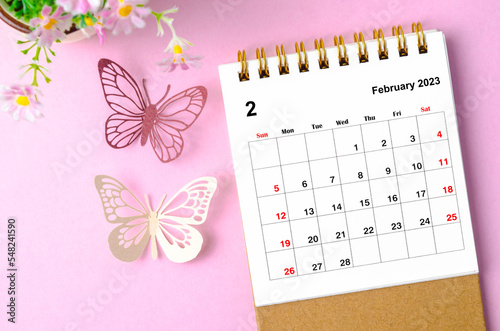 A February 2023 desk calendar for the organizer to plan and reminder and paer butterfly on pink colour background. photo