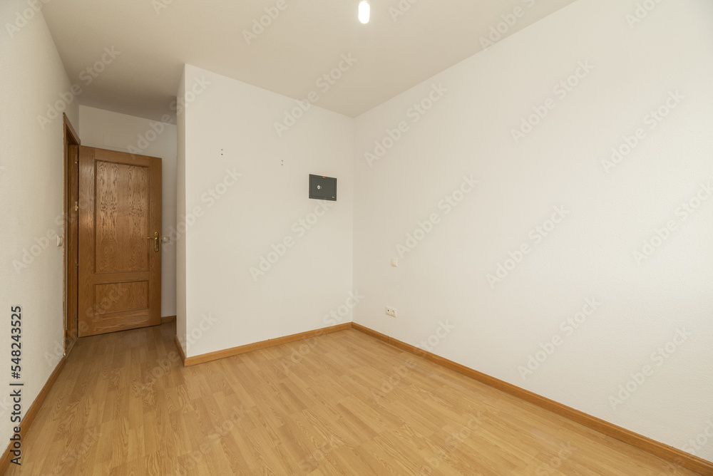 Empty living room with French oak parquet flooring with bare white walls and pinewood doors and a small built-in wall safe Empty living room with French oak parquet flooring with bare white walls and pinewood doors and a small built-in wall safe