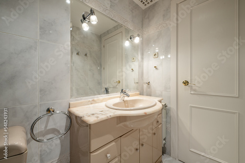 Classic bathroom with cream sanitary ware  beveled mirror embedded in the wall with white wooden door