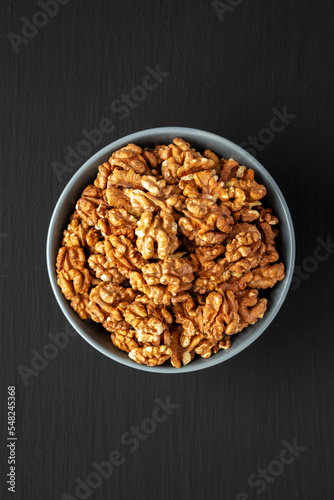Raw Organic Walnuts in a Bowl on a black background, top view. Flat lay, overhead, from above.