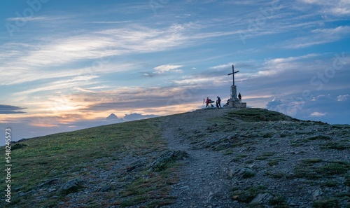 Cloudy blue sky over Matagalls peak with a cross and trekkers in the Montseny massif of Catalonia photo