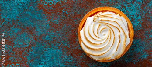 Delicious lemon curd and meringue tart, top view, on a bright rustic background with space for text