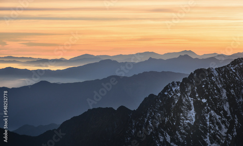 View of Himalayas mountain range with visible silhouettes through the colorful fog from Langtang top trek trail. Gosaikunda top in himalayan region Lantang, Nepal. Sunrise nature minimalism background