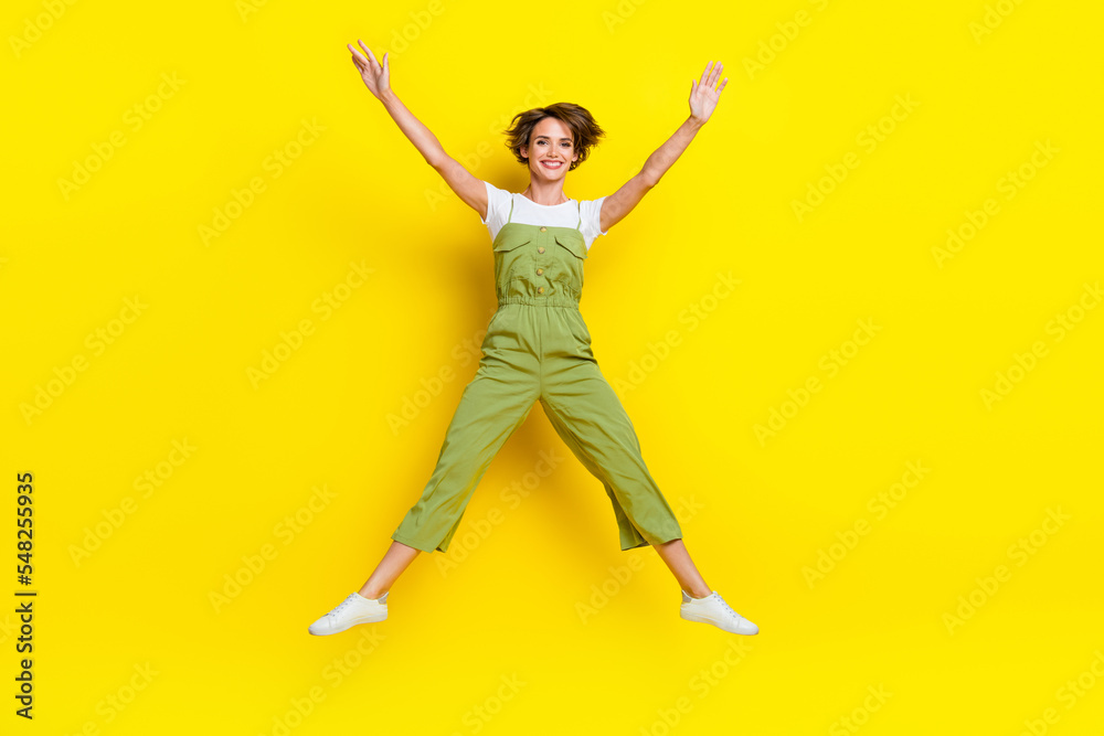 Full body length photo of carefree jumping funky girl hands up star symbol travel summer vacation positive mood isolated on yellow color background