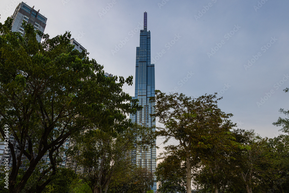 Obraz premium Ho Chi Minh City, Vietnam - November 08, 2022: Landmark 81, a building in Saigon. Landmark 81 among other high-rise buildings of Vinhomes Central Park urban area with a lawn and palm tree alley