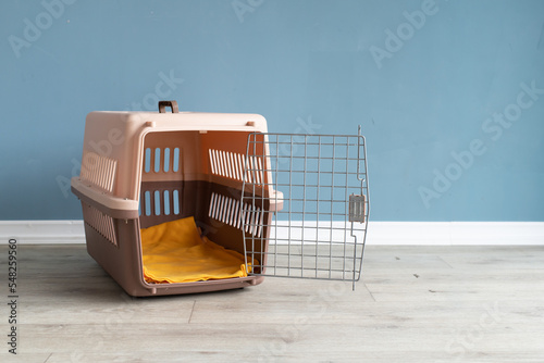 Opened plastic pet carrier or pet cage on the floor at home, copy space