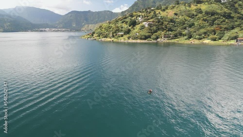 Aerial view of the Atitlan lake with a man sailing in a wooden paddle boat on a sunny day photo