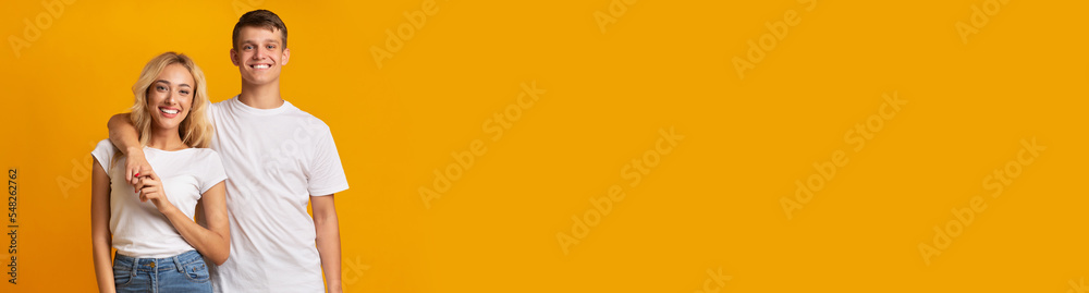 Cheerful young couple embracing and smiling on yellow Cheerful young couple embracing and smiling on yellow