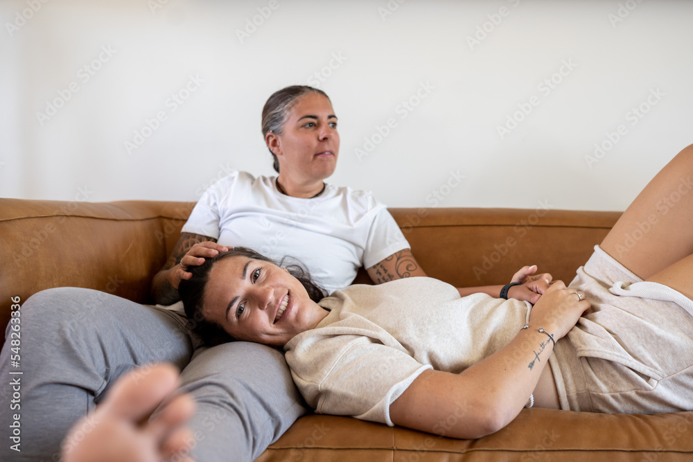 Fototapeta premium Adult lesbian couple sits and lies on couch at home