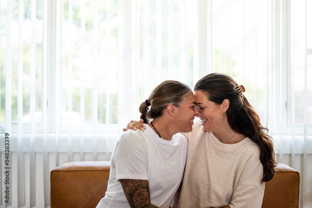 Adult lesbian couple intimate on couch at home Adult lesbian couple intimate on couch at home