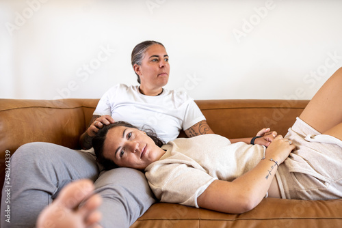 Adult lesbian couple sits and lies on couch at home