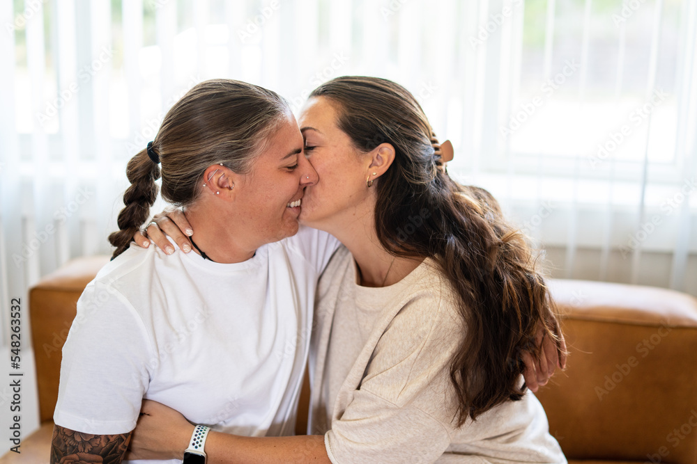 Adult lesbian couple kiss on couch at home Adult lesbian couple kiss on couch at home