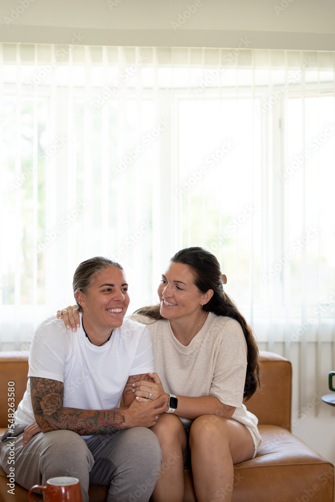 Adult lesbian couple comforting each other on couch at home Adult lesbian couple comforting each other on couch at home