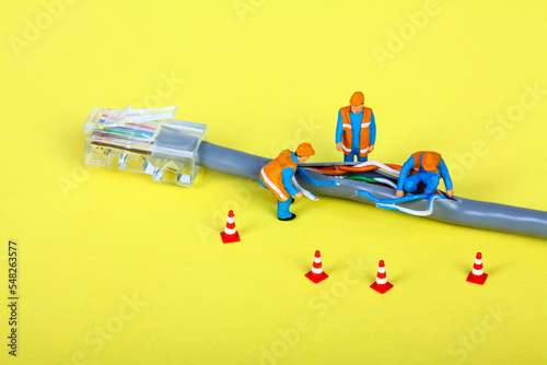 Conceptual image of miniature figure workmen investigating a fault on a broadband network cable