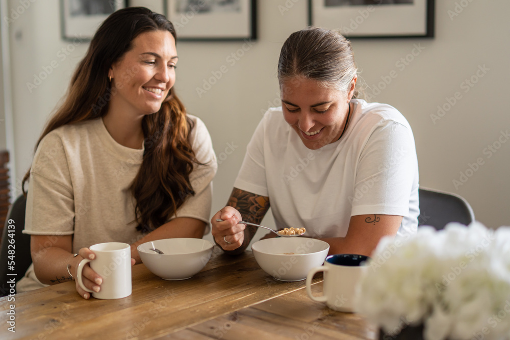 Adult lesbian couple have breakfast together in dining room Adult lesbian couple have breakfast together in dining room