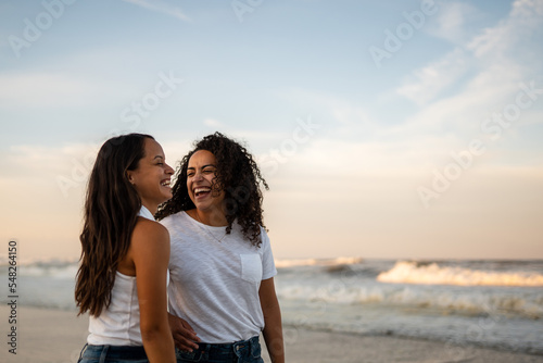 Hispanic lesbian couple stand by the ocean holding hands