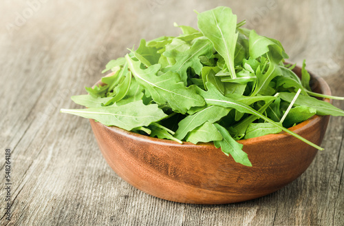fresh arugula leaves in a wooden plate on the table