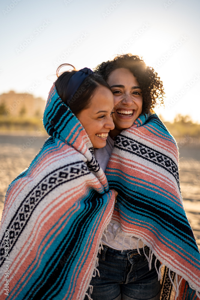 Hispanic lesbian couple uses blanket at beach