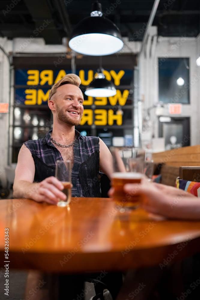 LGBTQ Friends sit at a bar with beer and champagne