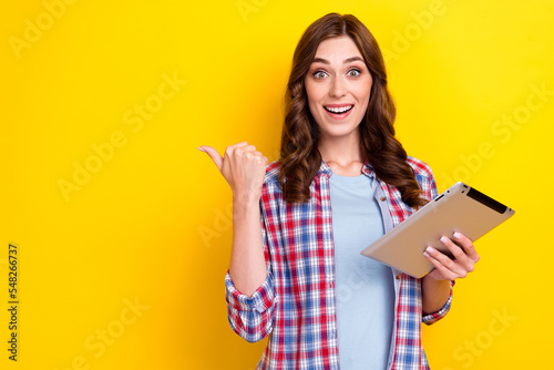 Closeup photo of millennial girl hold new tablet finger directing empty space free delivery eshopping worldwide isolated on yellow color background