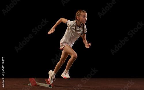 Focus on movement. Portrait of begginer athlete, runner training isolated on black studio background. Concept of action, motion, speed, healthy lifestyle. photo