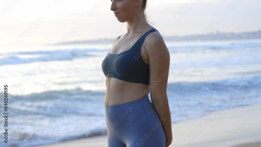 Young sporty woman doing yoga exercises and stretching at the beach with ocean view rolling sea waves at the coast. Young sporty woman doing yoga exercises and stretching at the beach with ocean view rolling sea waves at the coast.