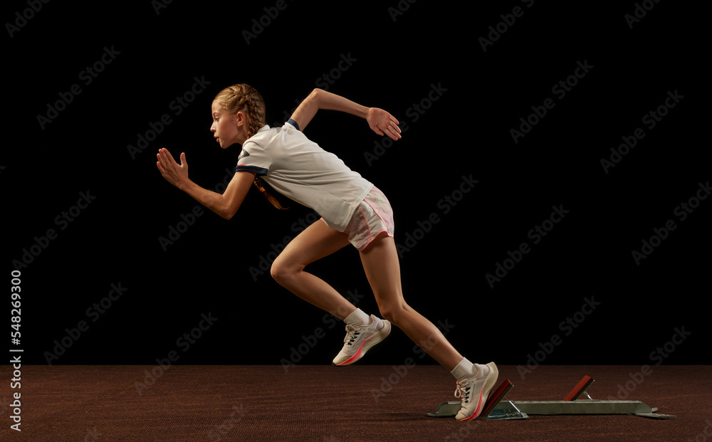 Focus on movement. Portrait of begginer athlete, runner training isolated on black studio background. Concept of action, motion, speed, healthy lifestyle.