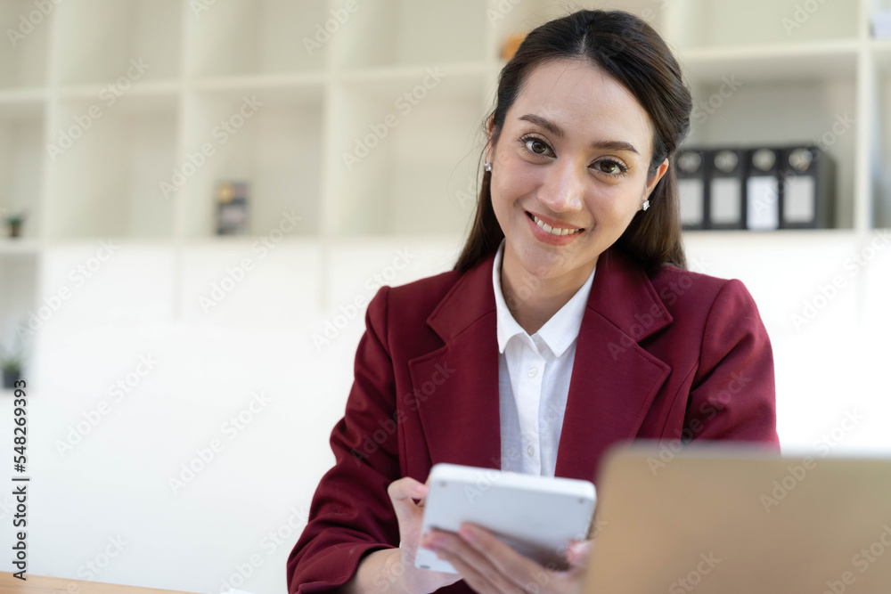 Asian Business woman using calculator and laptop for doing math finance on an office desk, tax, report, accounting, statistics, and analytical research concept Asian Business woman using calculator and laptop for doing math finance on an office desk, tax, report, accounting, statistics, and analytical research concept