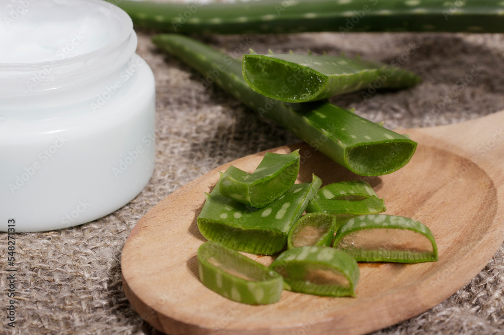 Aloe Vera leaf cut into pieces on a wooden spoon, next to natural cosmetics. The concept of using natural cosmetic products with natural ingredients. Aloe Vera leaf cut into pieces on a wooden spoon, next to natural cosmetics. The concept of using natural cosmetic products with natural ingredients.