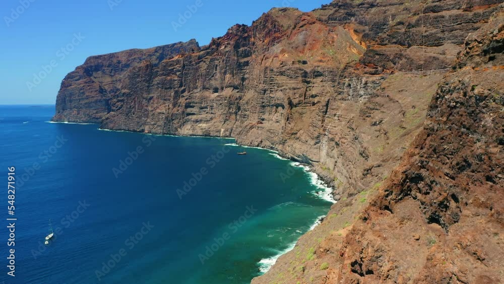 Steep mountainside over the ocean deep blue azure water and narrow dangerous mountain path on Los Gigantes cliffs. Tenerife Canary Islands. Steep mountainside over the ocean deep blue azure water and narrow dangerous mountain path on Los Gigantes cliffs. Tenerife Canary Islands.