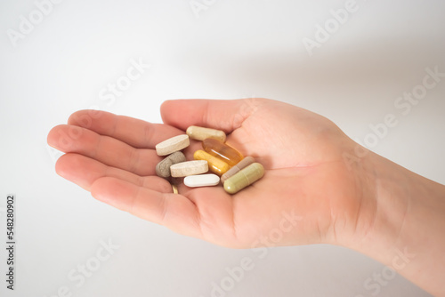 Hand with pills vitamins white background  