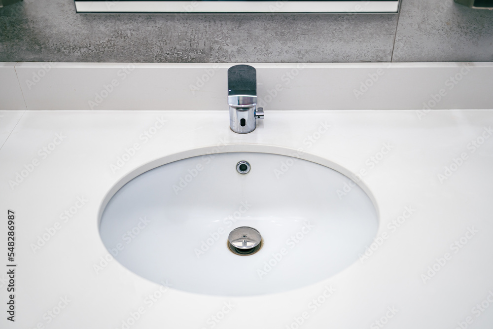 a round sink for washing hands and an automatic faucet for water in a public toilet a round sink for washing hands and an automatic faucet for water in a public toilet