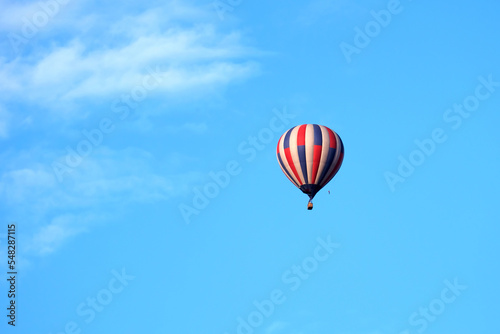 hot air balloon in flight with a basket, blue white balloon red color