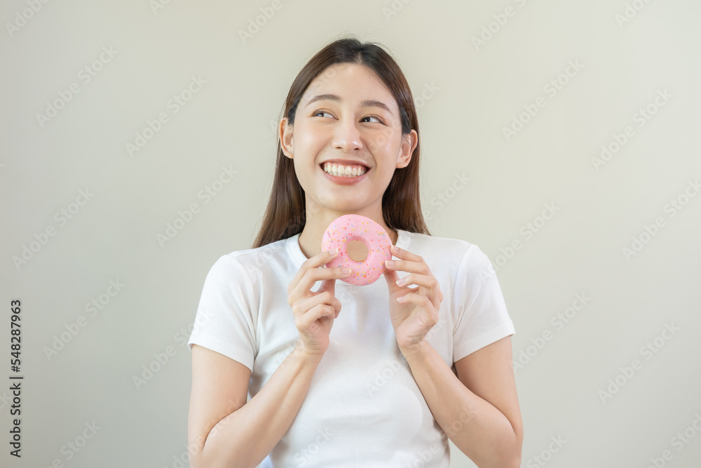 Portrait of attractive beautiful girl, pretty asian young teenage woman holding pink donut, doughnut, emotion enjoy sweet. Dieting, diet for loss weight to slim. Isolated white background, copy space. Portrait of attractive beautiful girl, pretty asian young teenage woman holding pink donut, doughnut, emotion enjoy sweet. Dieting, diet for loss weight to slim. Isolated white background, copy space.