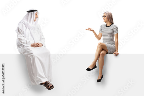 Casual young woman sitting on a white panel and talking to a mature arab man