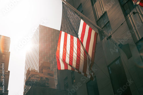 Photography An American flag glows in the sun in an urban landscape.