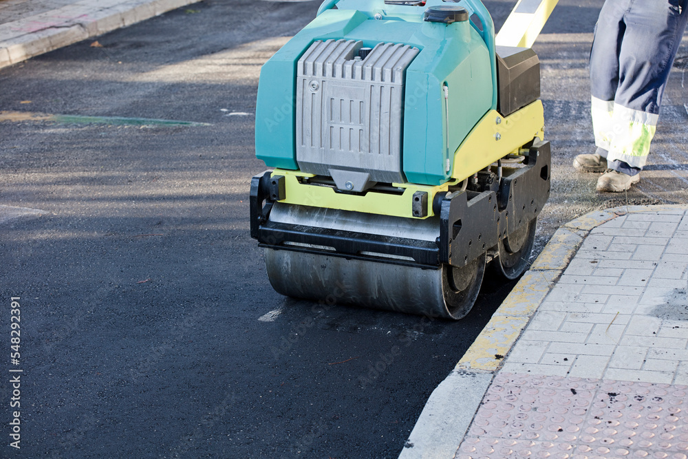 Road construction equipment flattening and smoothing asphalt black top lane