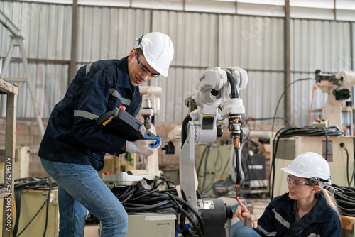 Robotics engineer working on maintenance of modern robotic arm in factory warehouse