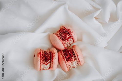 Pink large macaroons with raspberry filling on a pretty white cloth.