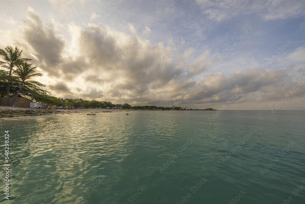 Spectacular views of coastline and turquoise waters of Caribbean sea at sunset blending into clouds on horizon. Aruba.