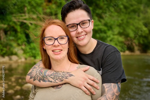 Same sex female couple embracing looking at camera.