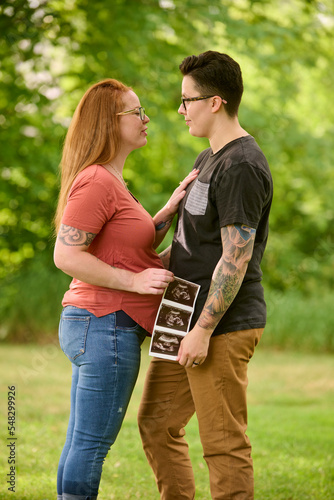 Same sex female couple holding ultrasound of unborn baby.