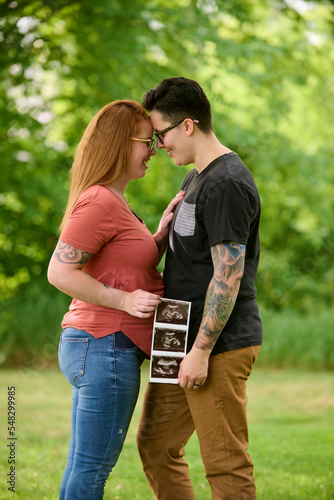 Same sex female couple holding ultrasound of unborn baby.