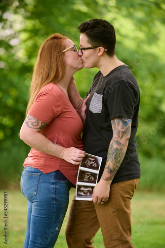 Same sex female couple holding ultrasound of unborn baby.